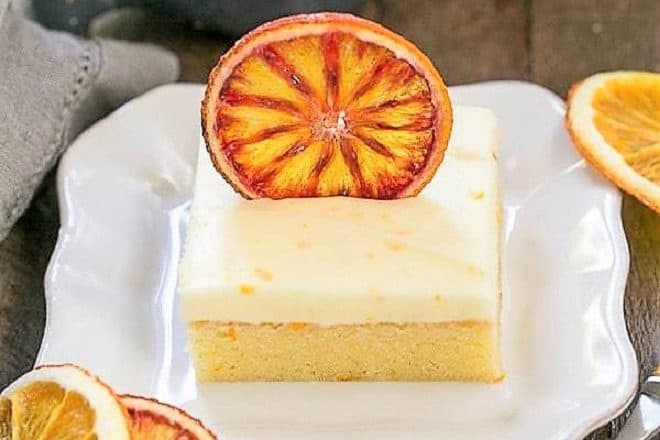 Orange Cake with Cream Cheese Frosting on a square white plate with dried orange slices