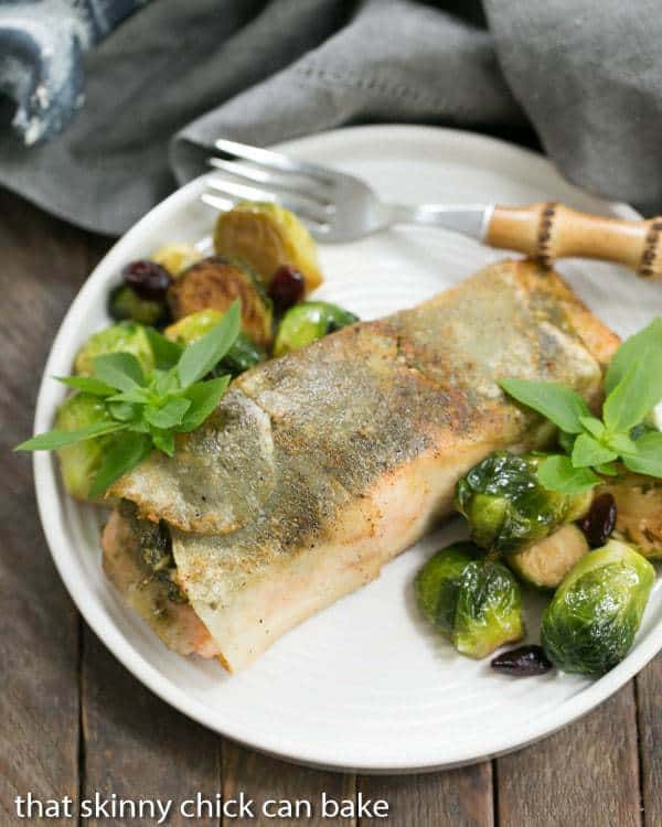 Potato Shingled Salmon on a white plate with brussels sprouts