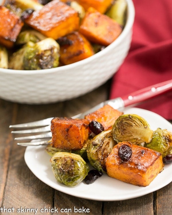 Roasted Autumn Vegetables on a small white plate with a bowl of roasted vegetables.
