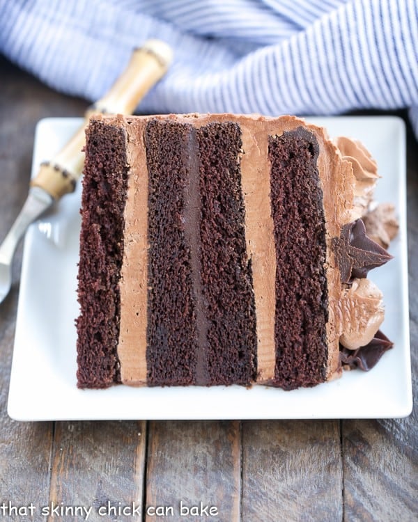 Chocolate Fudge Layer Cake slice on its side on a white square plate.