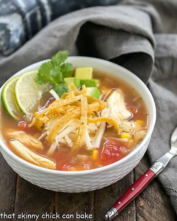 Leftover Turkey Tortilla Soup in a white bowl garnished with lime and cilantro sprigs.