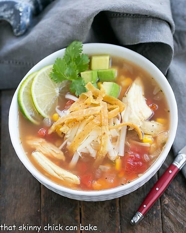 Leftover Turkey Tortilla Soup in a white bowl with a red handled spoon.