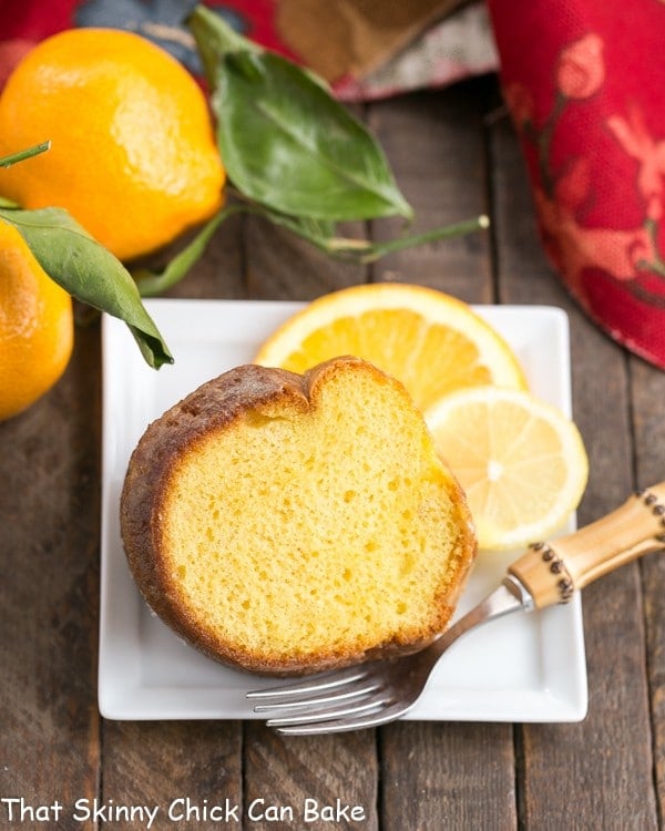 Easy Lemon Bundt Cake slice on a square white plate with lemon and orange slice garnishes.