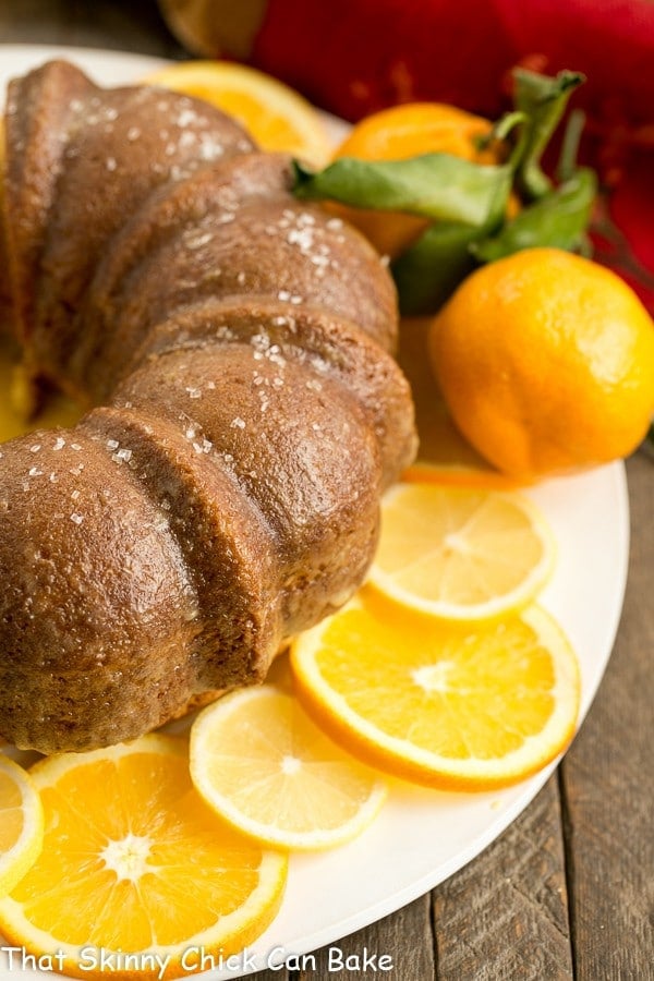 Easy Lemon Bundt Cake on a white cake plate with lemon and orange slices.