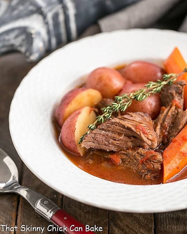 Easy Pot Roast in a shallow white bowl with a sprig of thyme.