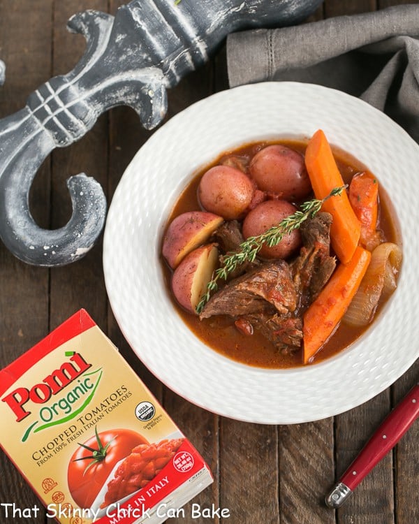 Easy Pot Roast overhead view in white bowl with a box of tomatoes