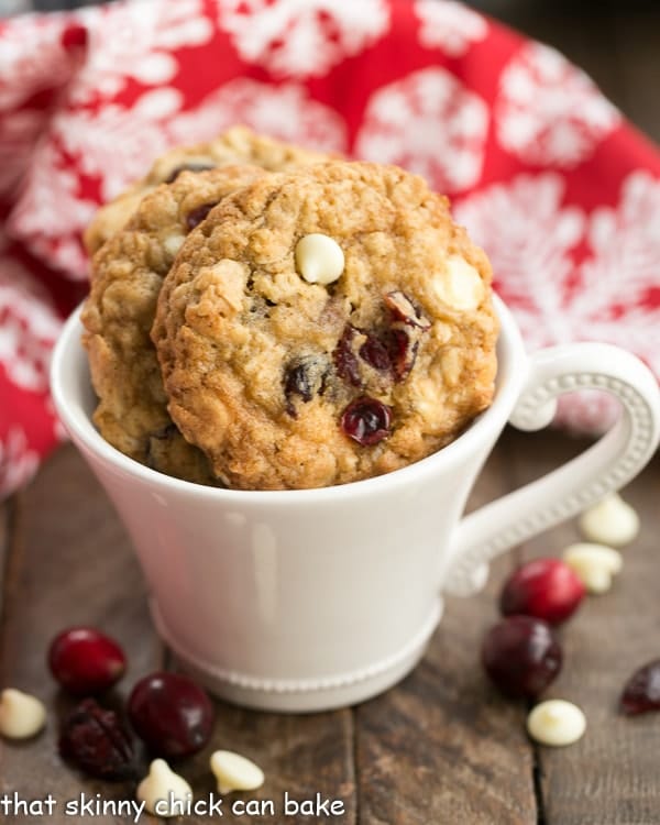 Easy Oatmeal Cookies with white chocolate and cranberries in a white coffee cup with cranberries and white chocolate chips.