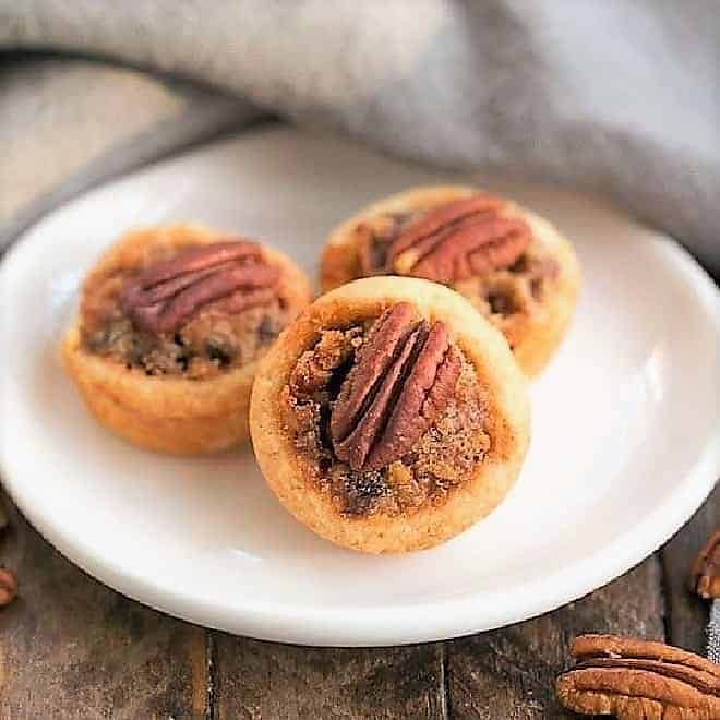 Pecan Tassies on a small white oval plate.