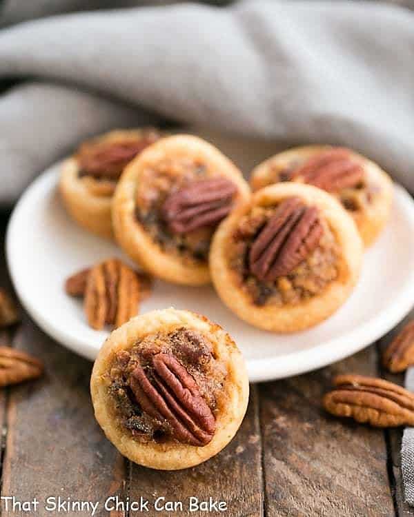 Pecan Tassies on a white plate with pecan halves.