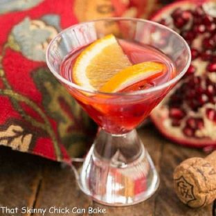 Pomegranate Champagne Cocktail garnished with orange slices in a small cocktail glass