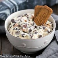 A bowl chocolate chip cookie dough dip in a white bowl with two Biscoff cookies