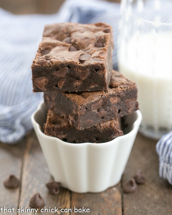 Fudgy Cocoa Brownies stacked in a fluted white ramekin.