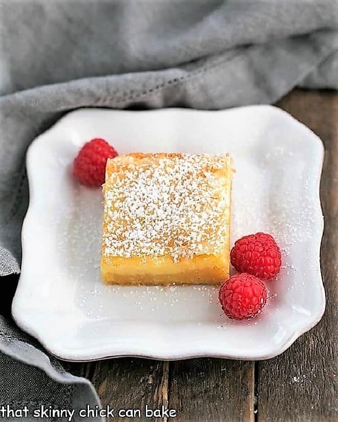 Gooey Butter Bars dessert on a plate with fresh raspberries.