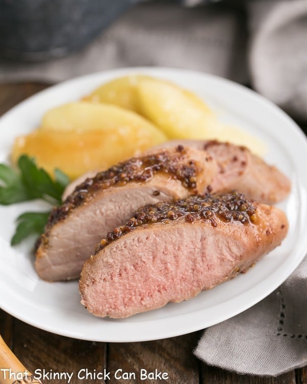 Close up of a plate of apple mustard pork tenderloin with apple slices.