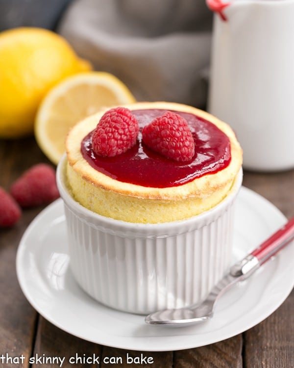 Raspberry Topped Lemon Soufflés in a white ramekin on a saucer with a red handled spoon.