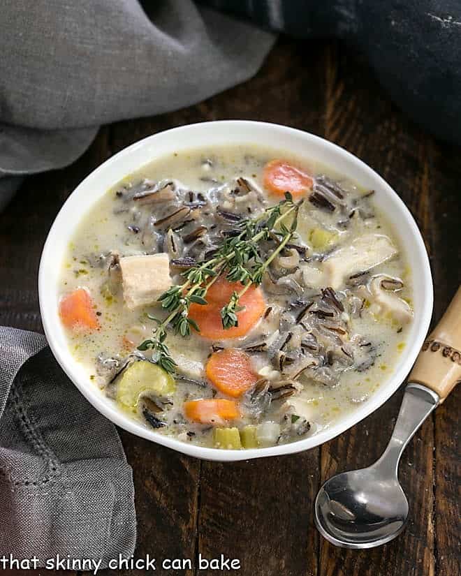 Overhead view of a bowl of wild rice soup with a bamboo handle spoon