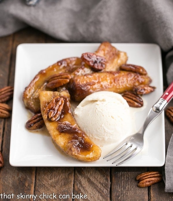 Bananas Foster on a square white plate with a scoop of ice cream.