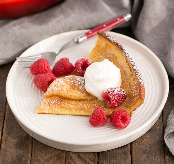 Best Dutch Baby Pancake | A puffed breakfast dish topped with berries, whipped cream and powdered sugar!