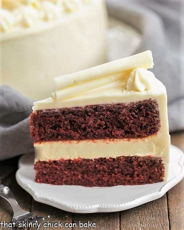 Slice of Cheesecake Filled Red Velvet Cake on a white plate