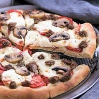 Sausage Mushroom Pizza with slice being removed from a pizza pan