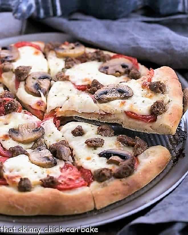 Sausage Mushroom Pizza with slice being removed from a pizza pan
