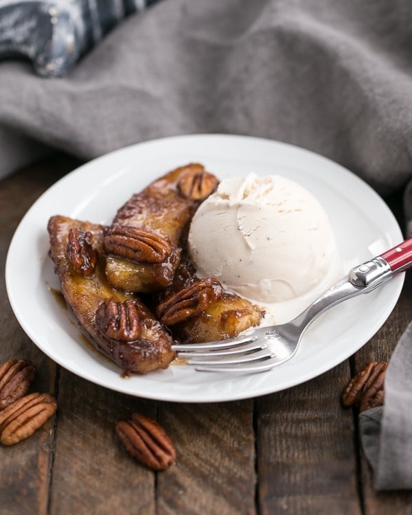 Bananas Foster with a scoop of ice cream on a round white plate.