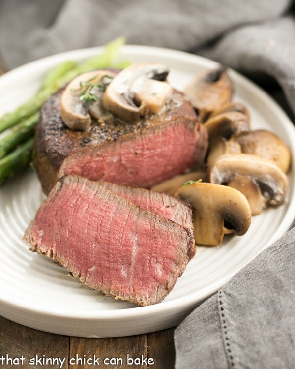 Mushroom Topped Pepper Steak fanned out on a white plate.