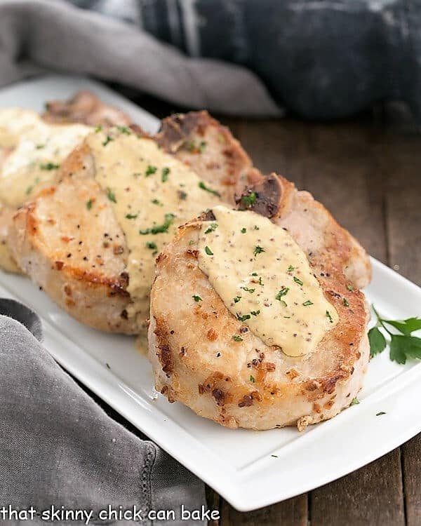 Pork Chops Dijonnaise on a rectangular serving tray with a drizzle of mustard sauce