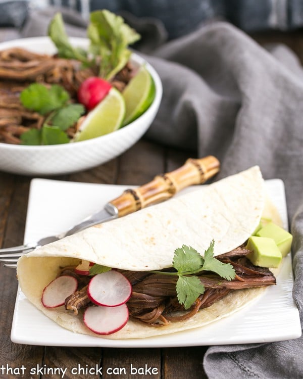 Slow Cooker Carne Asada in a tortilla on a square white plate