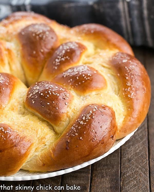 Braided Easter Bread is tender, slightly sweet, vanilla scented bread that is perfect to serve at a holiday brunch. This braided Easter bread recipe creates such a tender loaf of homemade egg bread, everyone will scramble for the last piece. #easter #recipe #bread Half of a loaf of Braided Easter Bread on a white platter.