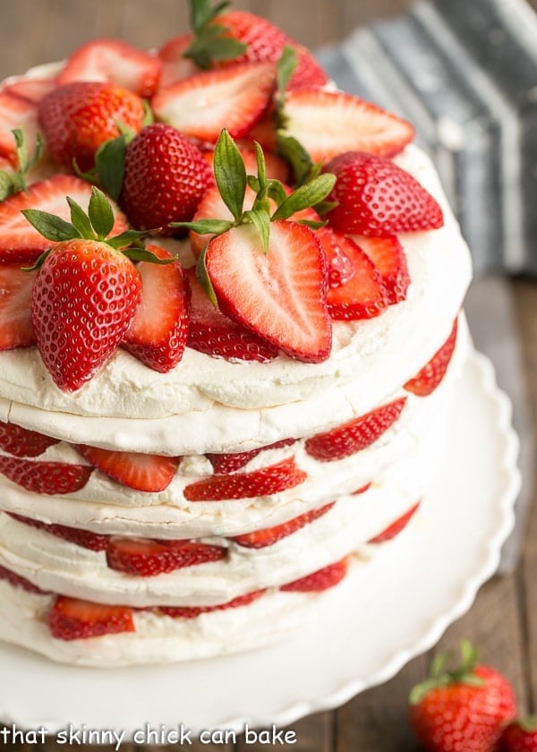 Side view of Fresh Strawberry Meringue Cake on a white porcelain cake stand.