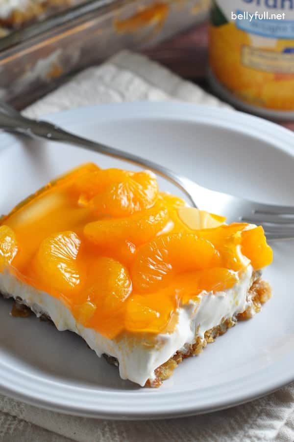Slice of Mardarin Orange Pretzel Dessert on a white plate with a fork