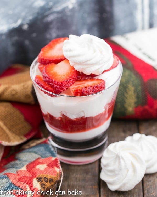 Parfait glass with Strawberry Eton Mess Fruit Parfait topped with a meringue cookie and sliced strawberries.