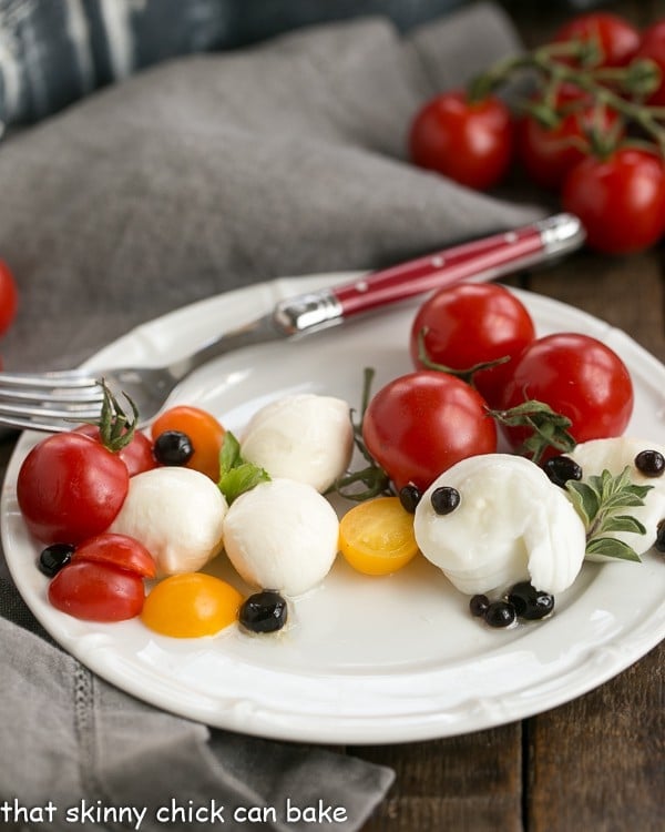 Side view of a Burrata Caprese Salad on a white plate with a fork