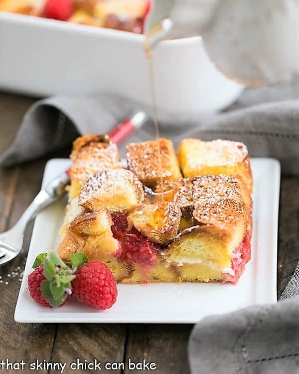 Raspberry Mascarpone French Toast Casserole on a white plate with a drizzle of maple syrup.
