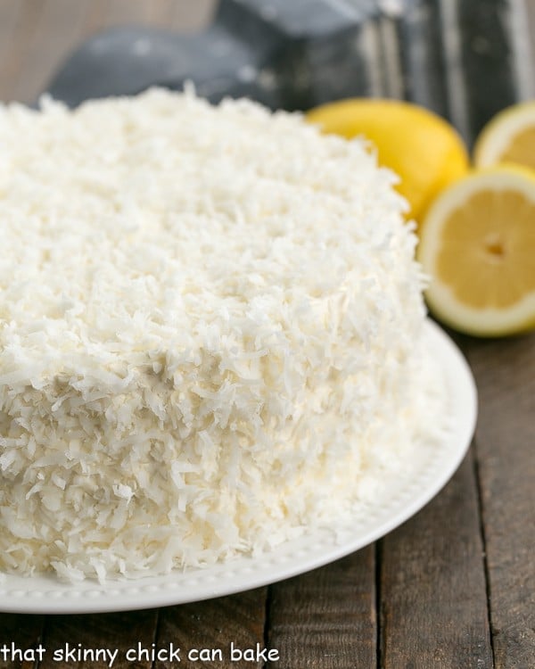 Lemon Layer Cake with Lemon Curd Filling and frosted with Lemon Swiss Meringue Buttercream and coconut on a white serving plate.