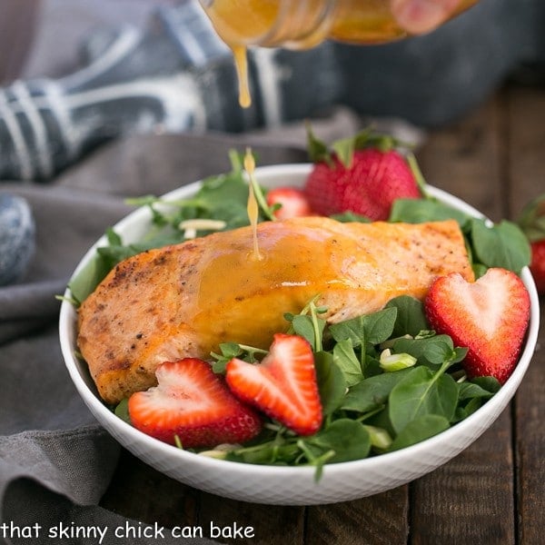 Dressing pouring over a Salmon Watercress Salad in a white salad bowl