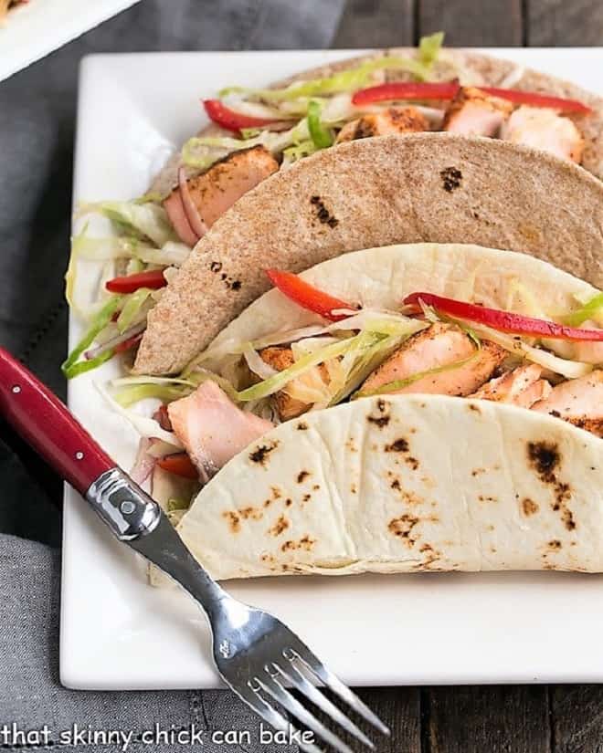  Two Salmon Tacos with Mango Salsa on a square white plate with a red handled fork