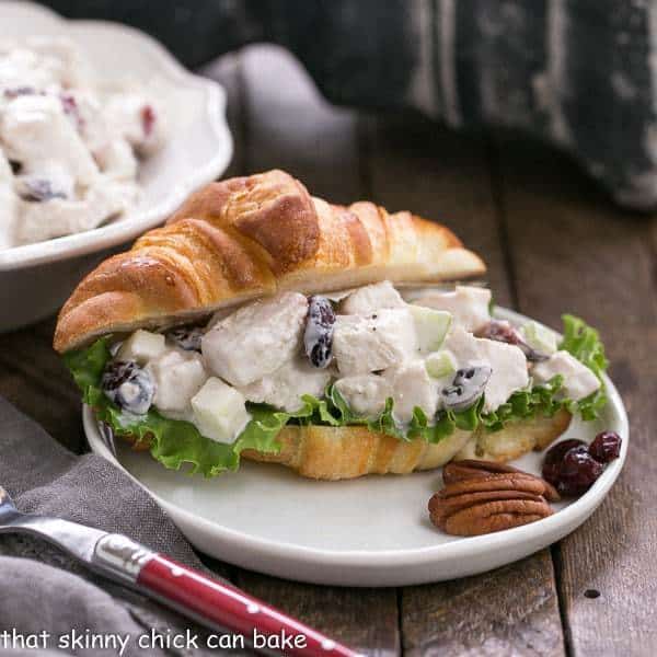Cranberry Pecan Chicken Salad on a croissant served on a small white plate.