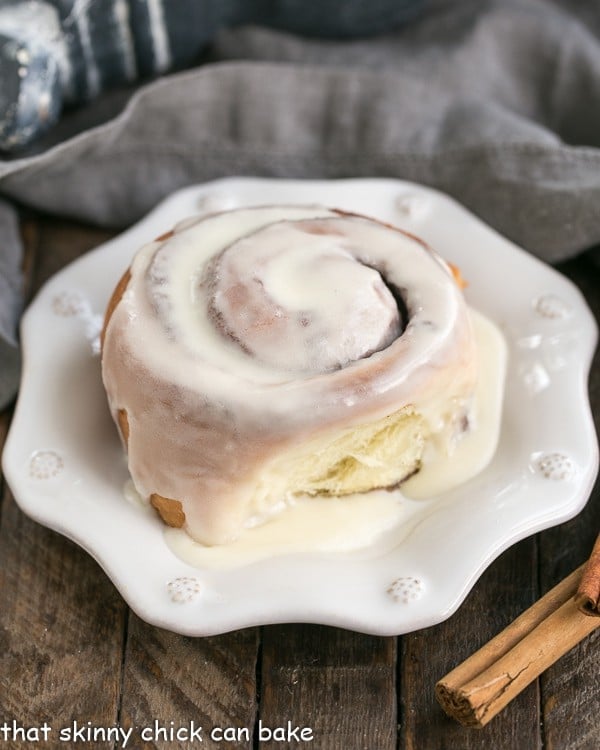 A close up of cinnamon bun on a decorative white plate