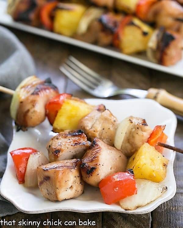 Plated Honey Glazed Chicken Kabobs on a small white plate with a serving platter in the background