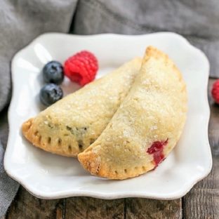 Rustic Berry Turnovers on a white plate with 3 berries