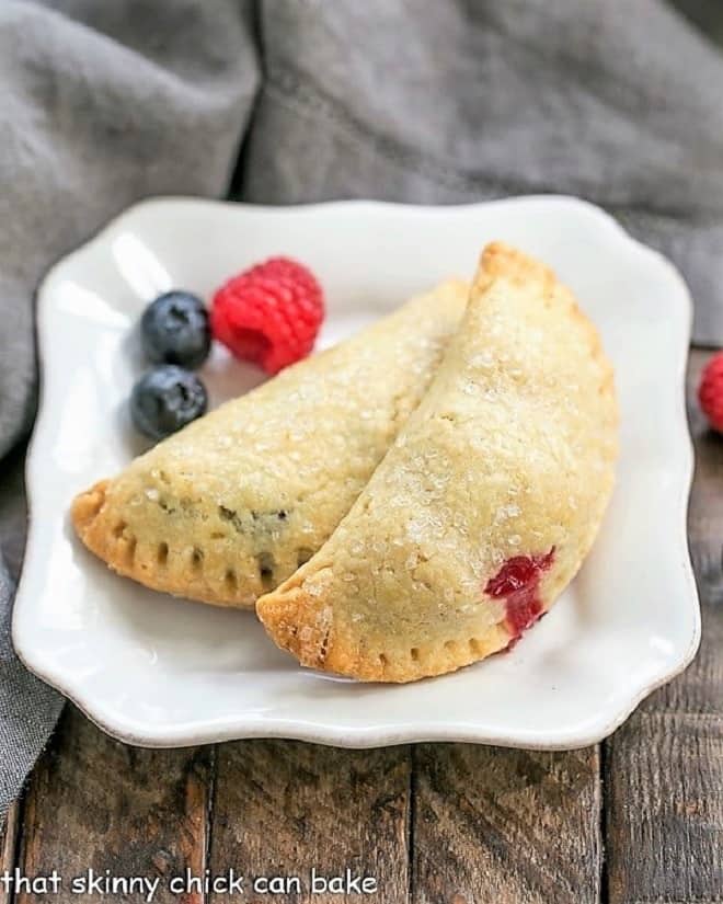 Rustic Berry Turnovers on a white plate with 3 berries.