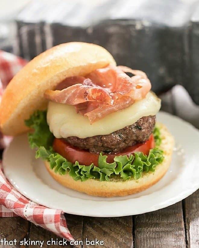 Italian Pesto Burger topped with cheese and prosciutto on a small white plate 