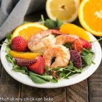 Shrimp salad on a white plate with citrus halves