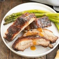 Apricot glazed baby back ribs on a white plate with asparagus