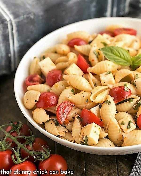 Tomato Basil Pasta Salad with Mozzarella & Fontina in a white ceramic serving bowl.