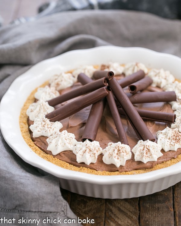 Chocolate Cream Pie in a white pie plate garnished with cream, chocolate curls and cocoa powder