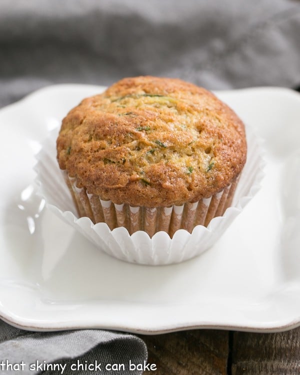 Cinnamon Zucchini Muffins on a white plate in a double white paper muffin wrapper