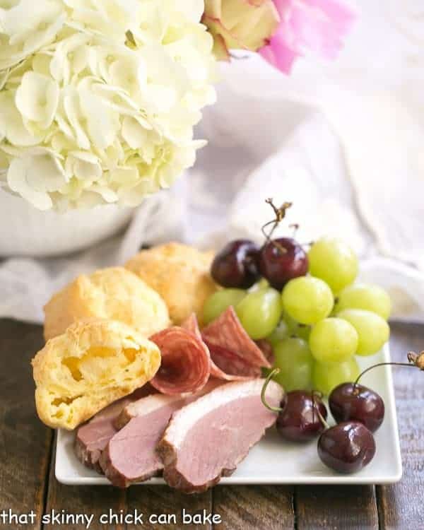 Triple Cheese Gougeres on a plate with charcuterie and fruit.